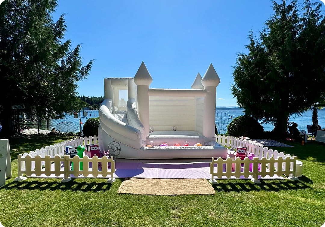 White bounce house rental in Bellevue backyard for a kids’ party with custom flooring and decor