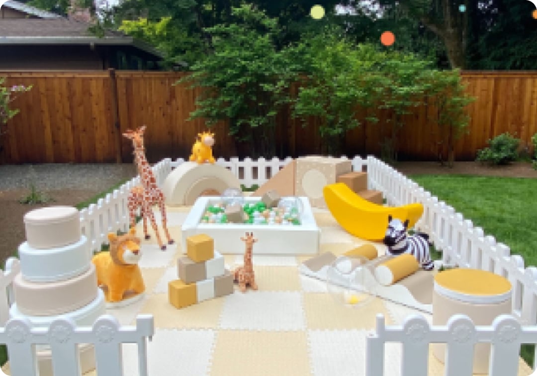 Safari-themed soft play rental setup in Issaquah backyard with animal figures and white fencing.